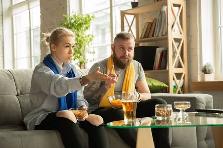 Excited family watching football, sport match at home. Beautiful caucasian couple cheering for...