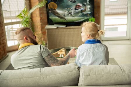 Excited family watching american football championship, sport match at home. Beautiful caucasian...