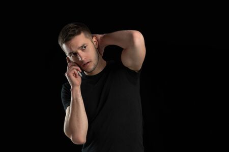Talking on phone. Monochrome portrait of young caucasian man isolated on black studio background....