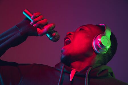 African-american mans portrait with headphones on gradient studio background in neon light....