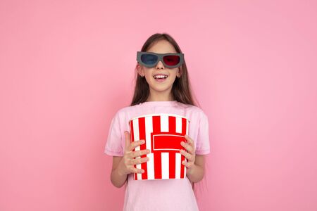 Wearing 3D-eyewear. Caucasian little girl portrait isolated on pink studio background. Cute brunette model in shirt. Concept of human emotions, facial expression, sales, ad, cinema. Copyspace.の写真素材