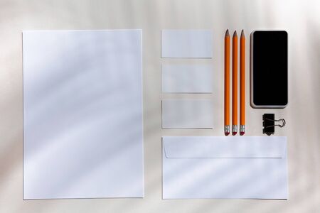 Sheets, gadgets and work tools on a white table indoors. Creative, cozy workplace at home office,...
