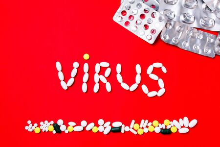 Weapon against COVID-19. Colored pills, tablets and capsules on a red background - history of treatment. Concept of healthcare and medicine, vaccine, prevention of pandemic, epidemic, chronic diseases.の写真素材
