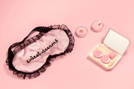 Lenses in case with mirror, sleep mask, candles. Monochrome stylish and trendy composition in pink color on studio background. Top view, flat lay. Pure beauty of usual things around. Copyspace for ad.の写真素材