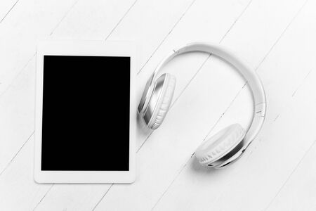 Tablet and headphones. Blank screen. Monochrome stylish and trendy composition in white color on studio background. Top view, flat lay. Pure beauty of usual things around. Copyspace for ad. Tech.の写真素材