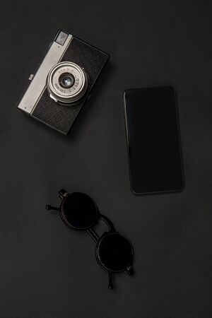 Gadgets and eyewear. Monochrome stylish and trendy composition in black color on studio background. Top view, flat lay. Pure beauty of usual things around. Copyspace for ad. Retro camera, smartphone.の写真素材