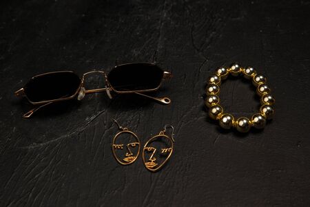 Accessories. Nailfile, eyewear, chain. Monochrome stylish and trendy composition in black and gold colors on studio background. Top view, flat lay. Pure beauty of usual things around. Copyspace for ad.の写真素材