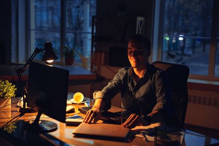 Done with deadline. Man working in office alone during coronavirus or COVID-19 quarantine, staying...