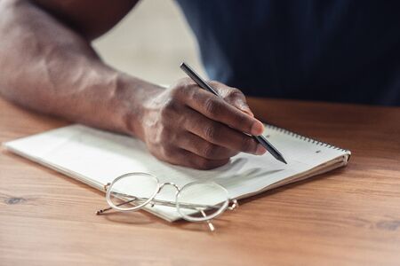 Writing. Close up of african-american male hands, working in office. Concept of business, finance, job, online shopping or sales. Copyspace for advertising. Education, communication and freelance.の写真素材