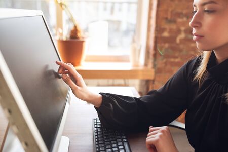 Touching blank screen. Caucasian young woman in business attire working in office. Young...
