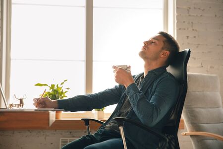 Creative workplace - organized work space as you like for inspiration. Man working in office in comfortable attire, relaxed position and messy table. Choose atmosphere you want - ideal clear or chaos.の写真素材