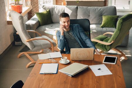 Creative workplace - organized work space as you like for inspiration. Man working in office in comfortable attire, relaxed position and messy table. Choose atmosphere you want - ideal clear or chaos.の写真素材