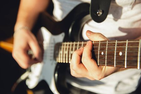 Caucasian musician playing guitar during online concert at home isolated and quarantined. Using camera, laptop, streaming, recording courses. Concept of art, support, music, hobby, education.の写真素材