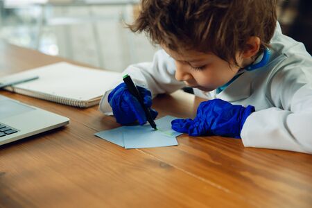 Caucasian teenboy as a doctor consulting for patient, giving recommendation, treating. Little doctor during prescriptioning drugs for patient. Concept of childhood, human emotions, health, medicine.の写真素材