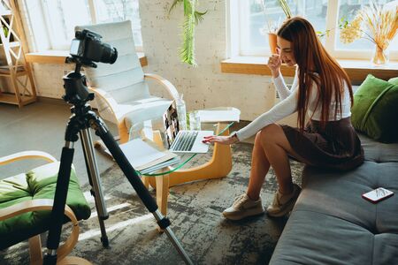 Caucasian woman singing during online concert at home isolated and quarantined. Using camera, laptop, streaming, recording courses, dancing. Concept of art, support, music, hobby, education.の写真素材