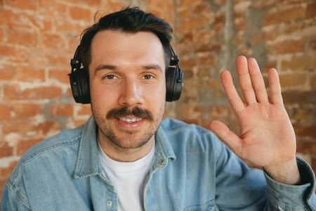 Caucasian musician in headphones greeting audience before online concert or sound-check at home...