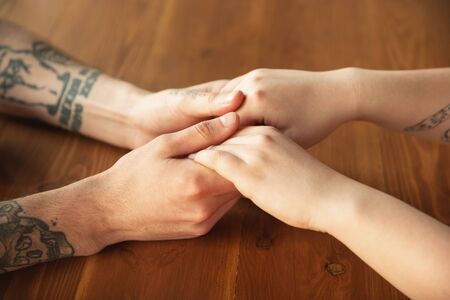 Loving caucasian couple holding hands close-up on wooden background. Romantic, love, relation,...