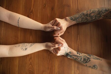 Loving caucasian couple holding hands close-up on wooden background. Romantic, love, relation,...