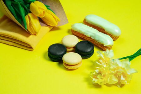 Macaroons and flowers. Monochrome stylish and trendy composition in yellow color on studio...