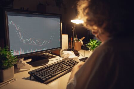 Working with graphs. Man working in office alone during COVID-19 quarantine, staying to late night....
