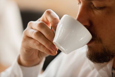 Drinking coffee. Close up of caucasian male hands, working in office. Concept of business, finance,...