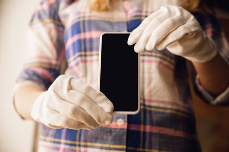 Coronavirus. Novel coronavirus 2019-nCoV , COVID-29, hands of a woman in protective gloves hold smartphone with blank screen with copyspace. Devices, gadgets, technology, safety concept.の写真素材