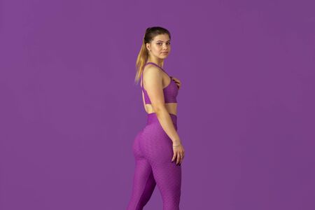 Grace. Beautiful young female athlete practicing in studio, monochrome purple portrait. Sportive caucasian fit model posing confident. Body building, healthy lifestyle, beauty and action concept.の写真素材