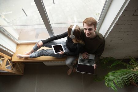 Attractive young couple using devices together, tablet, laptop, smartphone, headphones wireless....