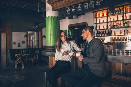 Cheerful caucasian man and woman talking, enjoying at the coffee shop, cafe, bar. Couple or friends, business partners drinking toghether, having a date, romantic. Communication, relations concept.の写真素材