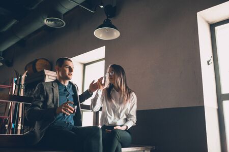 Cheerful caucasian man and woman talking, enjoying at the alco shop, cafe, bar. Couple or friends, having a date, romantic. Wearing casual attire. Emotional, smiling. Communication, relations concept.の写真素材