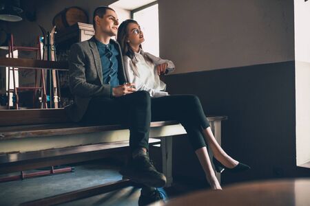 Cheerful caucasian man and woman talking, enjoying at the alco shop, cafe, bar. Couple or friends, having a date, romantic. Wearing casual attire. Emotional, smiling. Communication, relations concept.の写真素材
