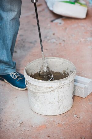 Closeup of repairman in uniform, professional builder working using construction equipment. Process of building, apartment renovation, repairing, building. Coloring, measuring, preparing the base.の写真素材