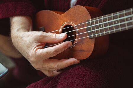 Playing on ukulele, guitar. Senior man during quarantine, realizing how important stay at home...