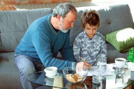 Useful time. Grandfather and his grandson spending time together insulated at home. Having fun,...