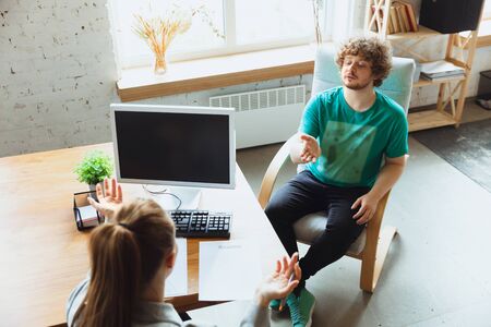 Young man sitting in office during the job interview with female employee, boss or HR-manager,...
