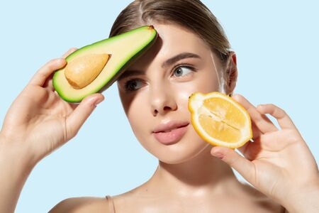 Close up of beautiful young woman with fresh lemon and avocado on white background. Concept of...