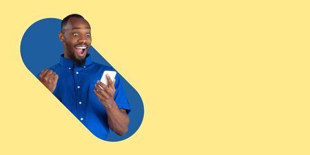 Portrait of young man on bright bicolor background. Beautiful african male model, crazy happy winner. Human emotions, expression, sales, ad concept. Youth culture. Modern artwork, design, trendy.の写真素材