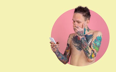 Portrait of young man on bright bicolor background. Unusual freaky look. Shocked scrolling on phone screen. Human emotions, expression, sales, ad concept. Youth culture. Modern artwork, design.の写真素材