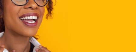 Smile with white teeth. African-american young womans portrait isolated on yellow studio background. Beautiful female curly model. Concept of human emotions, facial expression, sales, ad, youth.の写真素材