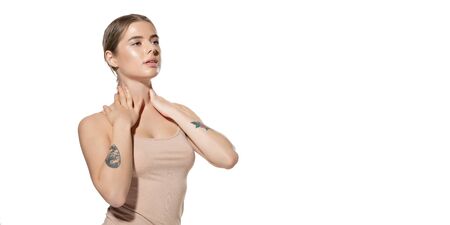 Portrait of beautiful young woman massaging her skin with moisturizer on white background. Concept of cosmetics, makeup, natural and eco treatment, skin care. Shiny and healthy skin, healthcare.の写真素材
