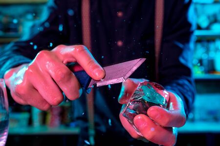 Close up of barman crushing a big piece of ice on the bar counter with a special bar equipment on it for a cocktail.の写真素材
