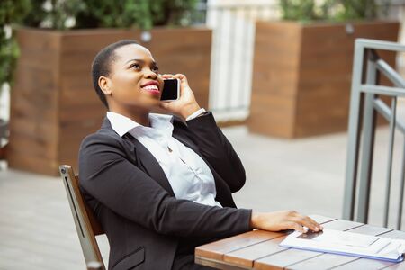 Communication. African-american businesswoman in office attire smiling, looks confident and happy, busy. Finance, business, equality and human rights concept. Beautiful young feme model, successful.の写真素材