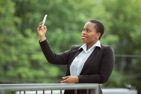 Selfie, videocall. African-american businesswoman in office attire smiling, looks confident and...