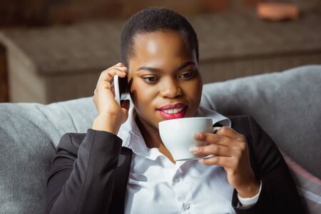 Business call. African-american businesswoman in office attire smiling, looks confident and happy, busy. Finance, business, equality and human rights concept. Beautiful young feme model, successful.の写真素材