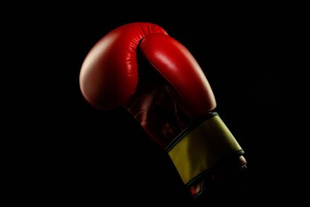 Boxers red glove. Professional sport equipment isolated on black studio background. Concept of sport, leadership, competition, healthy lifestyle in motion and action, training. Close up, copyspace.の写真素材
