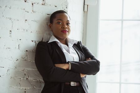 Hands crossed. African-american businesswoman in office attire smiling, looks confident and happy, busy. Finance, business, equality and human rights concept. Beautiful young feme model, successful.の写真素材