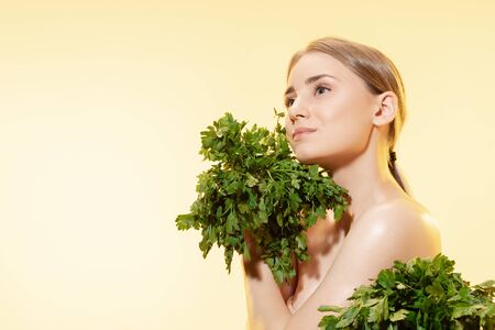 Close up of beautiful young woman with green leaves on white background. Concept of cosmetics, makeup, natural and eco treatment, skin care. Shiny and healthy skin, fashion, healthcare.の写真素材
