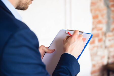 Taking notes, daily tasks, sitting on table. Young man, manager return to work in his office after...