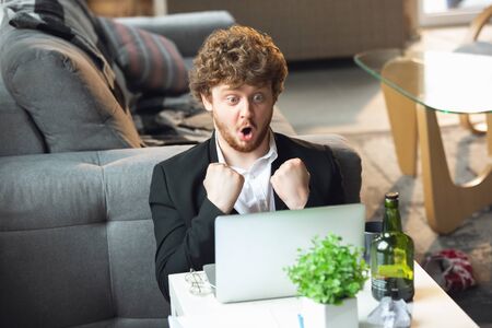 Success, winner. Man without pants but in jacket working on a computer, laptop. Remote office during...
