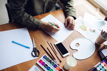 Close up of man drawing with paints and pencils at home. Comfortable atmosphere. Remote education, creative occupation, art therapy. Digitalization, using different devices, gadgets. Copyspace.の写真素材